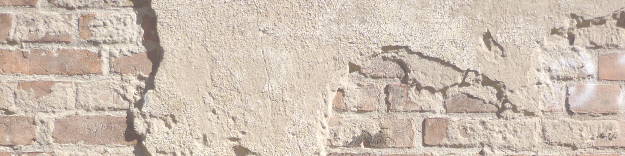 An old brick wall with chipped plaster